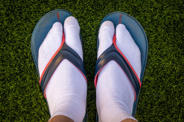 Feet in white socks and flip flops. Jandals.