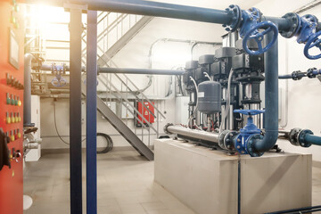 Industrial pumps in an engine room. Industry interior of water pump, valves, pressure gauges, motors inside technical room. Automatic control systems. Urban modern powerful pipelines. Copy text space