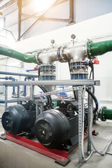 Urban modern powerful pipelines. Industrial pumps in an engine room. Industry interior of water pump, valves, pressure gauges, motors inside technical room. Automatic control systems. Copy text space
