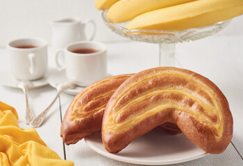 A crescent-shaped plate of fresh buns sits on a white wooden table.