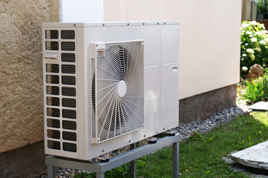 Heat pump or air conditioning outdoor unit in modern house of future using green electric energy, heat pump - efficient source of heat
