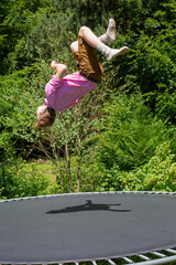 young man jumping on a trampoline outdoors in garden