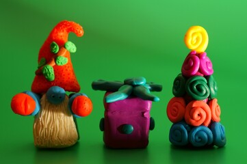A toy gnome with a Christmas tree and a gift on a green background. New Year and Christmas. Fabulous scenery.