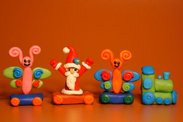 A toy train with butterflies and Santa Claus. A festive event. New Year and Christmas. Bright colored background.