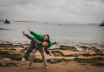 Young couple with the female on the boyfriends back posing on a rocky beach