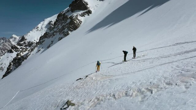 Aerial view skitouring freeride skier high in snowy mountains rides downhill in the company of friends