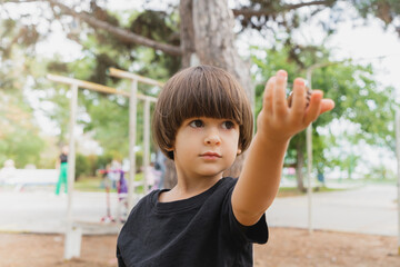 Smart little boy holding a toy in his hand on the playground outside brown hair