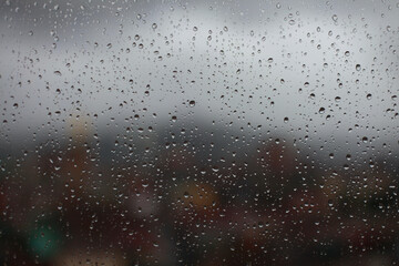 Water drops on window glass. City views soft focus.