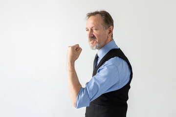 Portrait of grumpy mature businessman threatening with fist. Senior Caucasian manager wearing formalwear looking away in irritation. Business rivalry concept