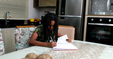 Fototapeta na wymiar Candid black teen girl studying at home doing homework