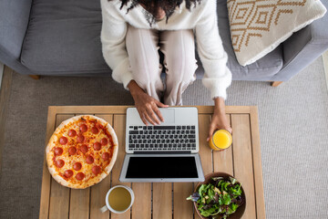 Businesswoman eating while working from home. Top view of African American woman sitting at desk,...