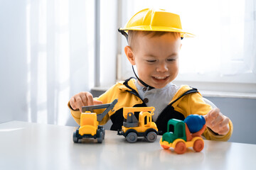 Fototapeta na wymiar Child play with construction machinery at home, dreams to be an engineer. Little builder. Education, and imagination, purposefulness concept. Boy with digger