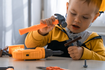 Child play with work tools at home, dreams to be an engineer. Little boy builder. Education, and imagination, purposefulness concept. Kid and hummer - 534323673