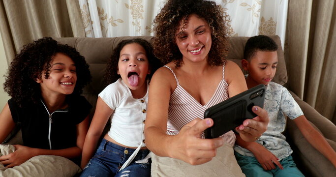 Brazilian mother and kids take selfie photo on couch with smartphone
