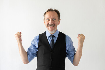 Portrait of successful mature businessman celebrating triumph. Senior Caucasian manager wearing formalwear looking at camera and making winning gesture against white background. Success concept