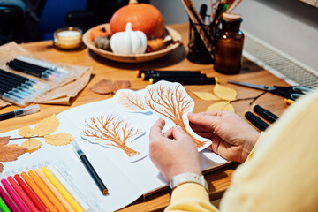 Autumn craft for adults. Faceless portrait of woman drawing autumn trees with markers and cutting...