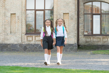 two schoolgirls in uniform walking together outdoor