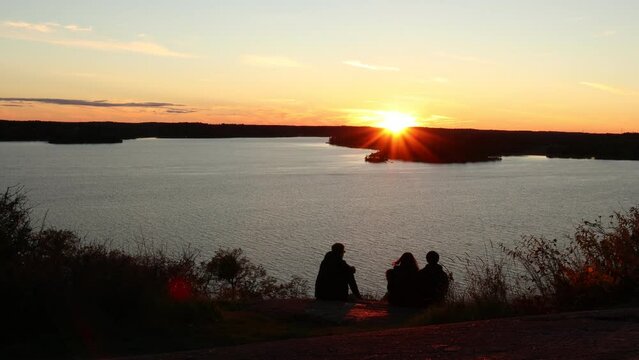 Beautiful sunset over the Swedish lake Malaren. People enjoying the last sun beams. Sunny dramatic and amazing horizon. Nice sky in September. Rear view.  Stockholm, Sweden, Euro