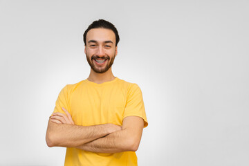 young bearded latin and hispanic man looking at camera and smiling with crossed arms. White background.
