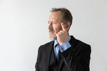 Portrait of pensive mature businessman looking away. Senior Caucasian manager wearing three piece suit standing touching his head and thinking against white background. Contemplation concept