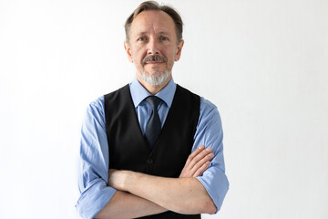 Portrait of confident mature businessman with folded arms. Senior Caucasian manager wearing formalwear standing and looking at camera against white background. Mature businessman concept