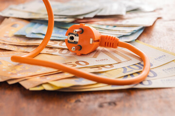 Electric plug and euro money on wooden table. Concept of increasing electric prices.