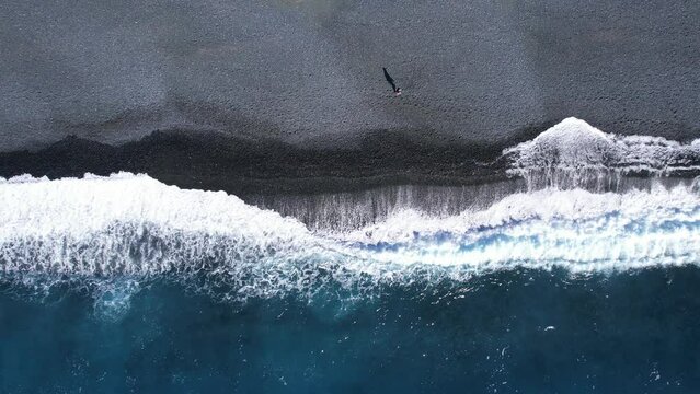 vue a&eacute;rienne d'un homme marchant au bord de la plage noire de Nonza - Cap Corse