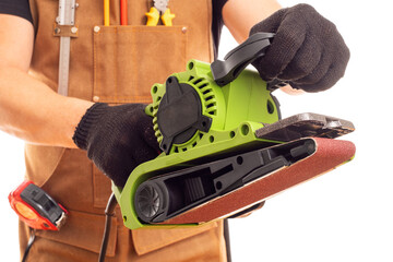 Carpenter in workers apron holding belt electric sander on white background