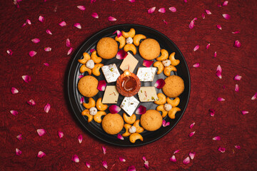Diwali Diya on red background, Sweets OR Mithai in indian thali  arranged over decorative background. Selective focus, Indian festival
