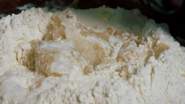 Adding kefir to flour for baking homemade balls of kolobok.