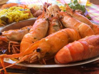 Closeup of Delectable spicy freshly cooked prawns on a metal plate and curry rice in the backgroung