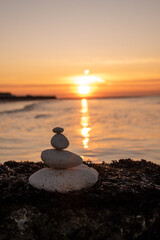 Stones stack together by the beach against the sunset. 