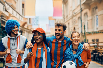 Cheerful sports fans have fun while going on soccer match during world championship.