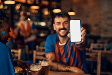 Close up of sports fan showing smart phone with blank screen in pub.