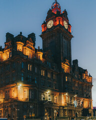 Vertical shot of a hotel and clock tower building at night in Edinburgh, Scotland