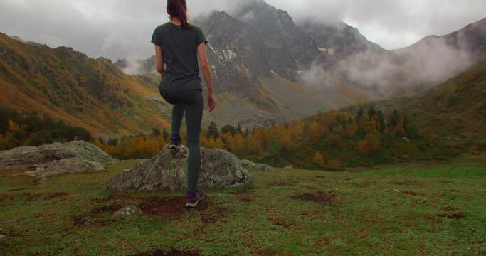 Full wide shot of woman stands in mountain enjoying the landscape