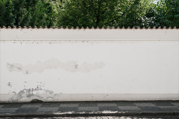 Long old concrete wall covered with white plaster at city street. Cement fence exterior with copy space and mockup.