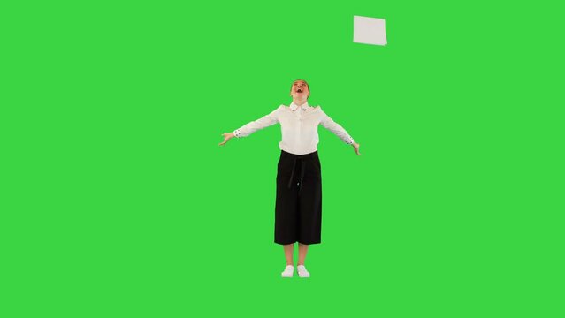 Positive caucasian girl throws away office papers and start dancing happily on a Green Screen, Chroma Key.