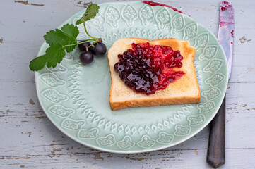 Leckeres Toastbrot mit Johannisbeeren Marmelade auf dem Teller mit Messer