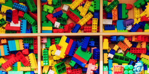 Fototapeta na wymiar Colorful plastic construction blocks for children development lying in wooden container
