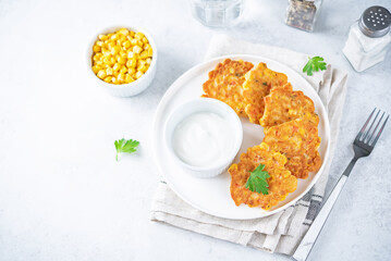 Corn fritters in a plate with sour cream sauce