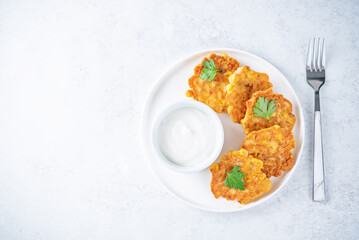 Corn fritters in a plate with sour cream sauce