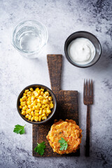 Corn fritters in a plate with sour cream sauce
