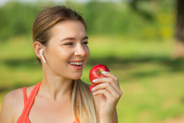 Active athletic sportive woman in sport outfit eating apple after the training