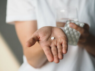 A woman holds a little round pill or vitamin in the palm of her hand. Female going to take tablet...