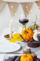 Idea for a beautiful autumn setting for thanksgiving family dinner or wedding. Orange pumpkin as decor. Cozy fall home atmosphere.