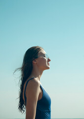 a joyful woman in sunglasses stands against the sky and the wind blows her wet hair