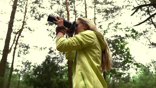A girl bird watcher taking pictures of birds in the woods