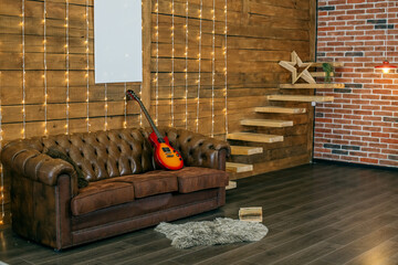 Loft style room interior with leather sofa and wooden wall. Electric guitar and book in room.