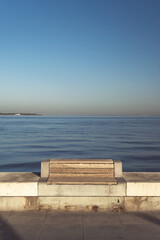 Fototapeta na wymiar Empty wooden bench near the waters edge morning sunlight